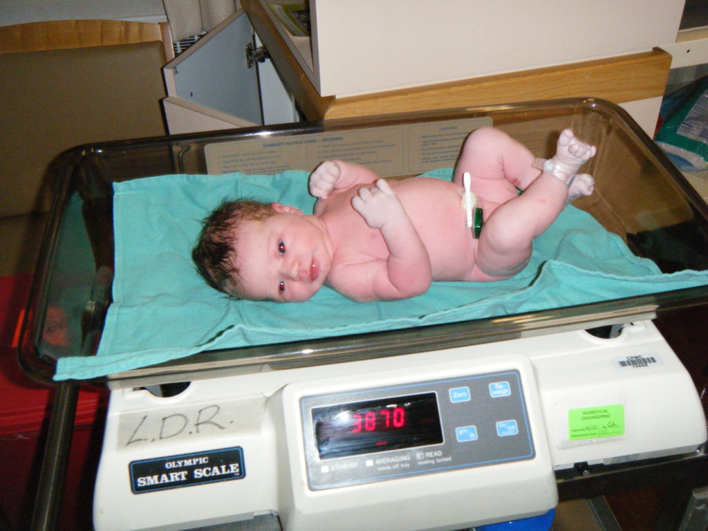 Newborn baby on weight scale in hospital Stock Photo